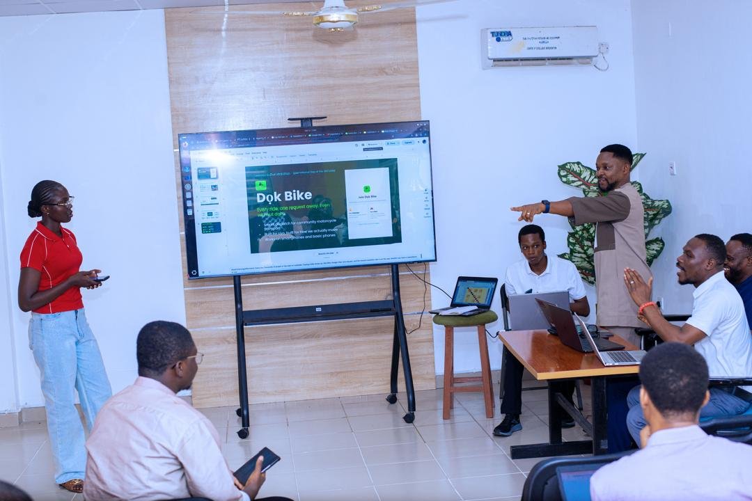 People gathered in a teaching room while two presenters stand beside a large screen